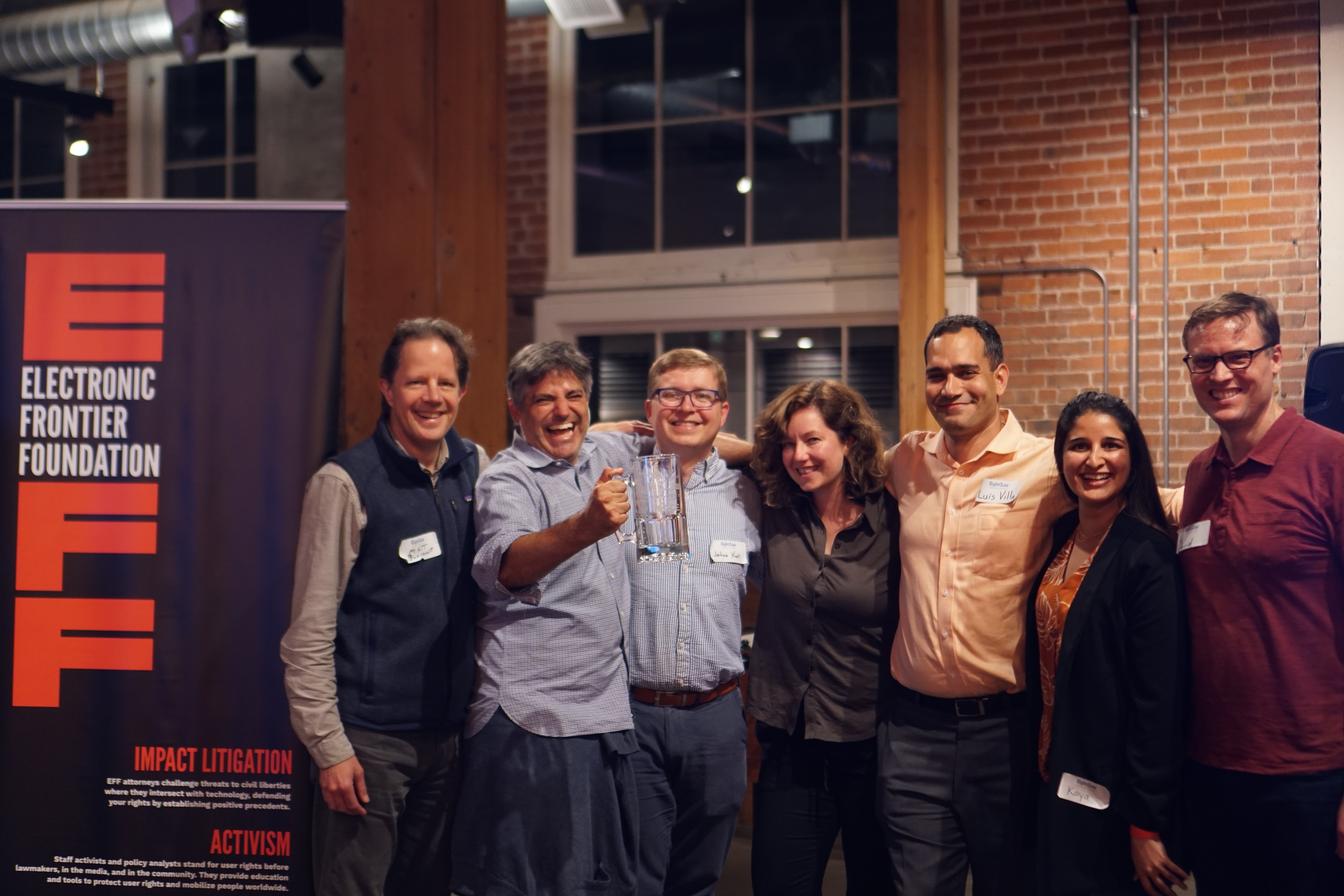 "Huawei or the Highway" "Huawei or the Highway". This is a photo of several people holding glass 3nd place mugs standing next to an EFF banner