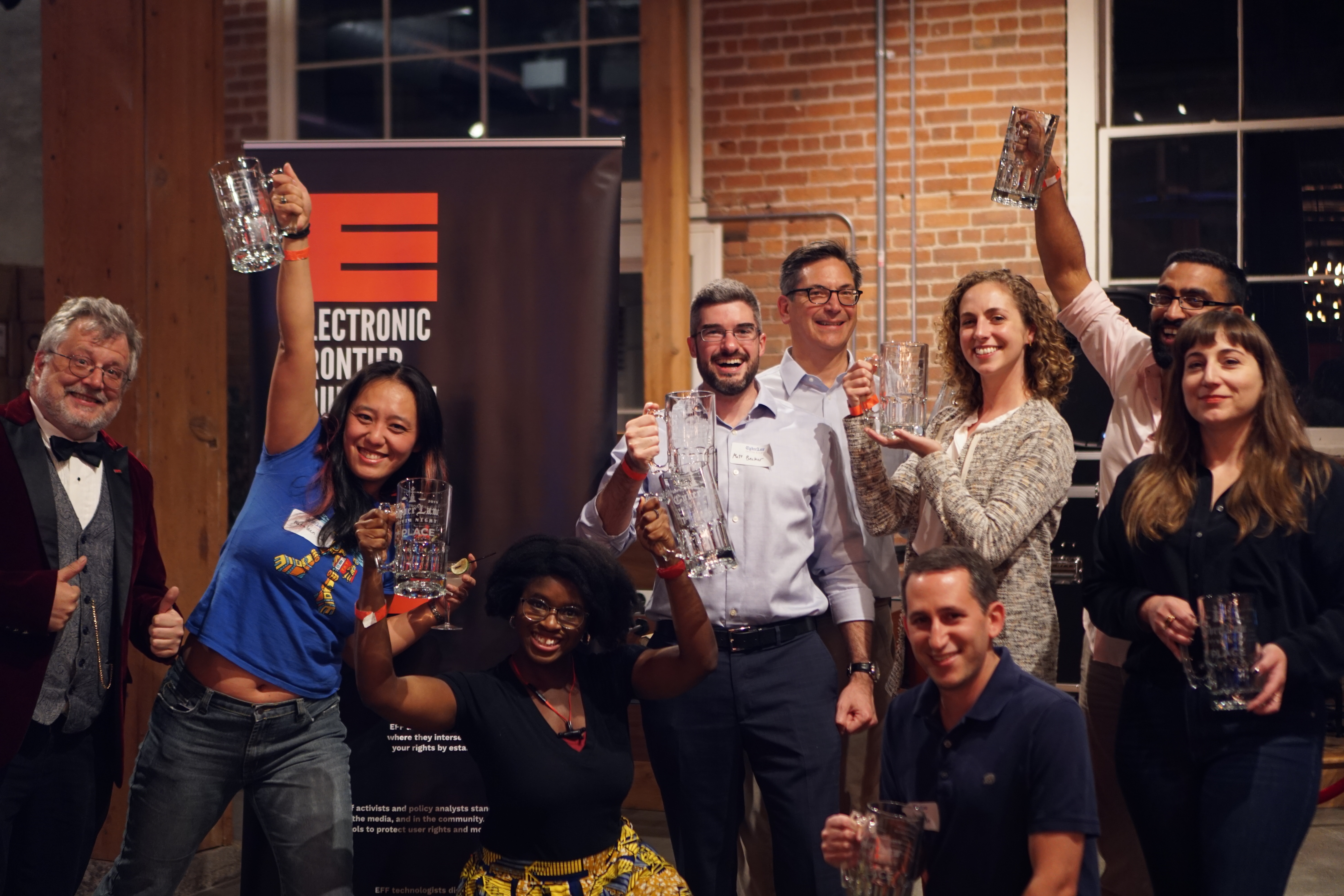 "F.U.C.T. (Fenwick Underwrites Cyberlaw Trivia)" "F.U.C.T. (Fenwick Underwrites Cyberlaw Trivia)" This is a photo of several people holding glass 1st place mugs standing next to an EFF banner, as well as a man in a stylish purple suit—Quizmaster Kurt!