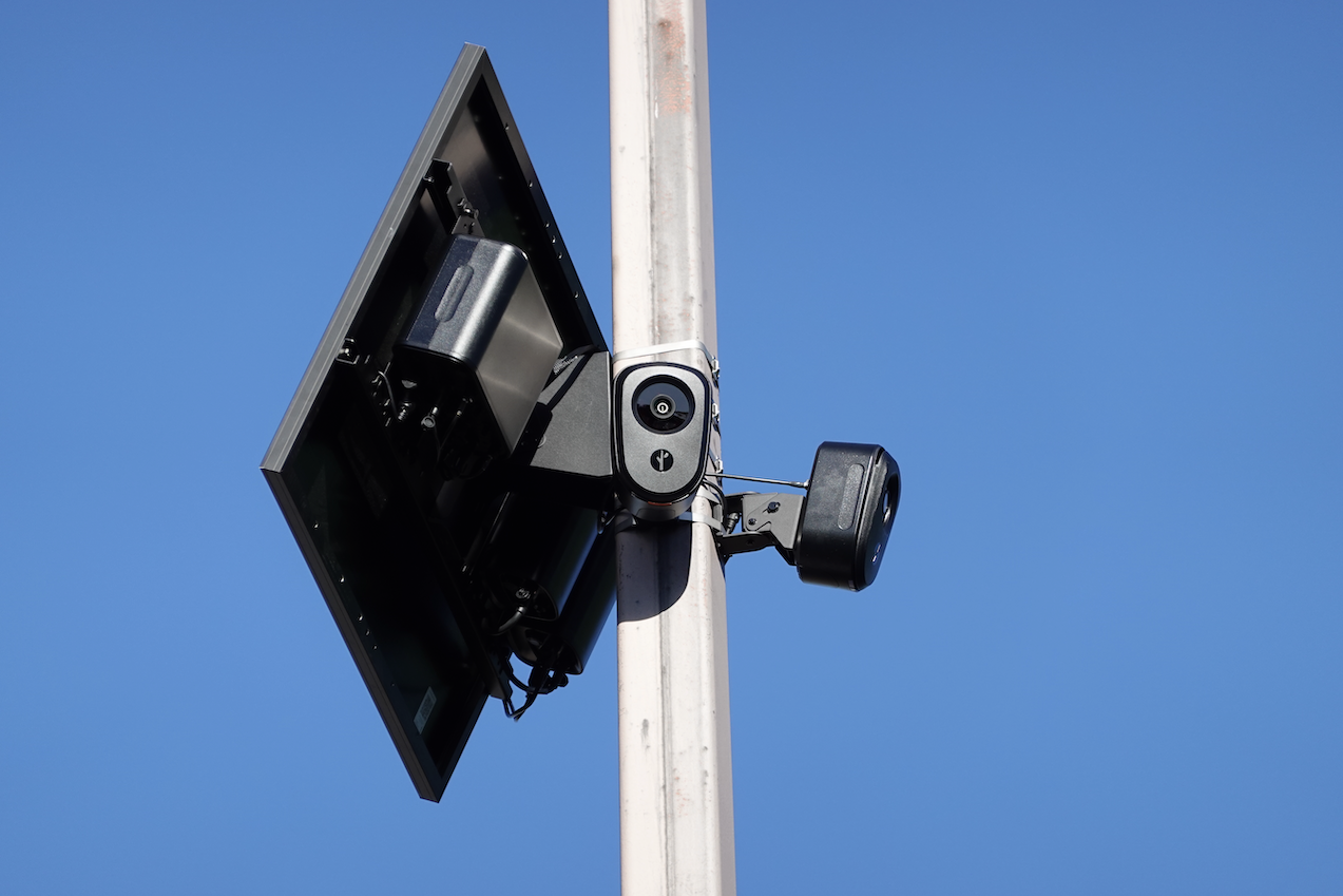 A pair of Flock Safety cameras on a pole, with a solar panel A pair of Flock Safety cameras on a pole, with a solar panel